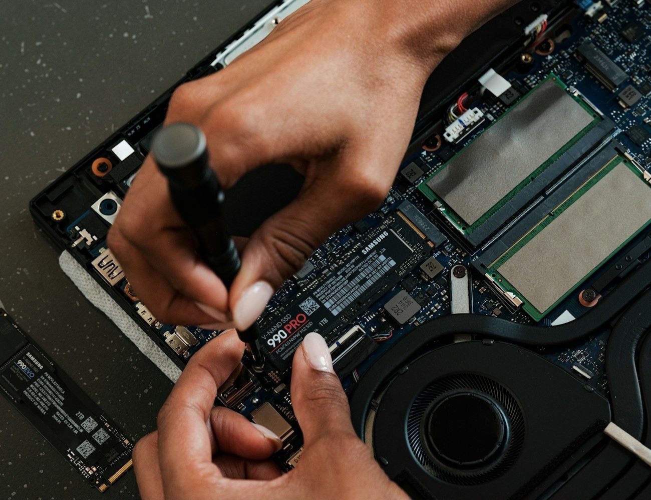 Hands installing an SSD in a laptop