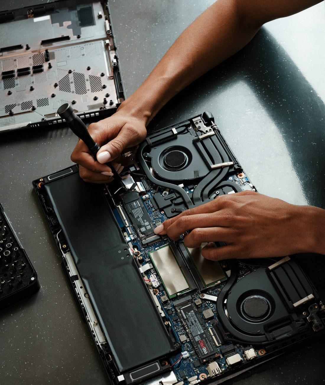 Hands repairing a laptop motherboard